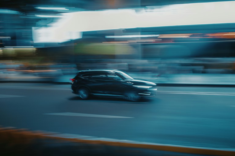 A side-view of a car as it speeds down a road.