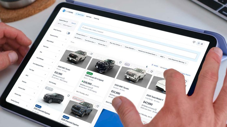 Person using a tablet to shop for cars. The tablet shows a white webpage with images of vehicles and their price.