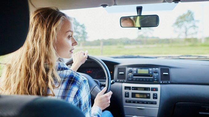 Teenage female in the driver's seat of a car.