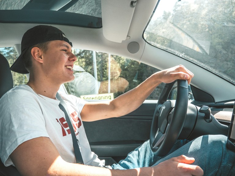 Teenage male in the driver's seat of a car.
