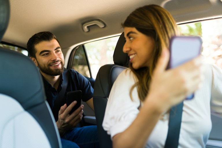 Man entering the backseat of a ride-share. A woman is in the driver's seat.