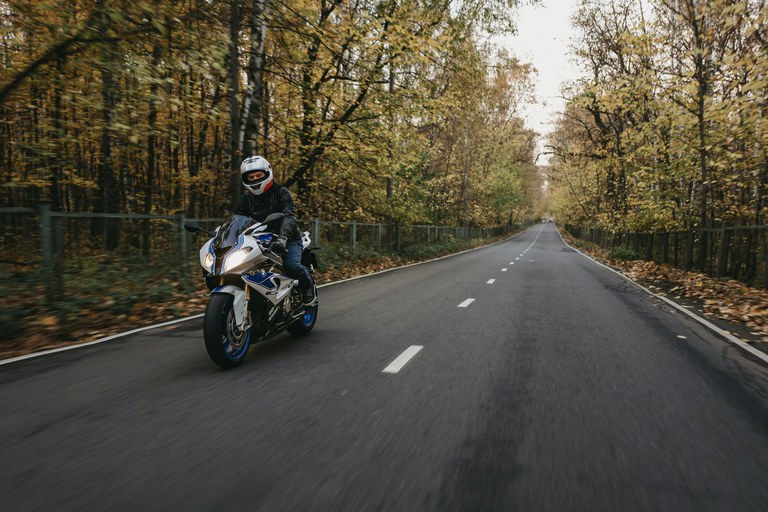 Motorcycle crash liability Motorcyclist on an open road with trees on both sides.
