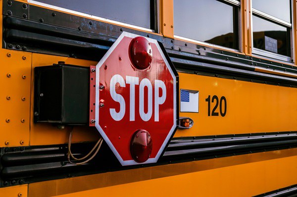 Yellow school bus with a red stop sign.