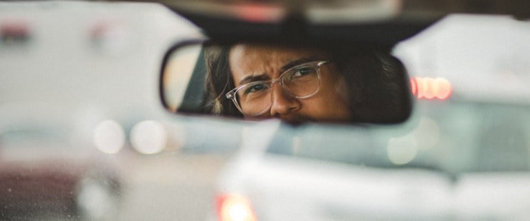 A woman glaring into her rearview mirror in the car
