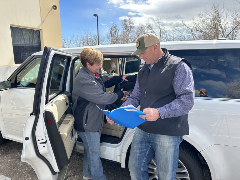 Angel Giffin, Colorado State Patrol’s Child Passenger Safety Training Coordinator, and Andrew Koldeway, a student from the course, stand outside a car reviewing instructions on proper car seat installation as they work on a car seat.  