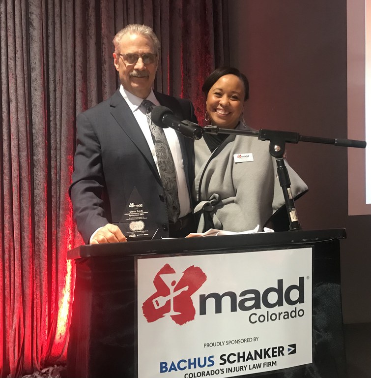 Glenn Davis (CDOT) and Rebecca Green (MADD) pose behind the MADD podium at the annual Tie One On for Safety breakfast.