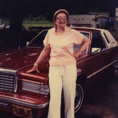 older lady standing in front of a car